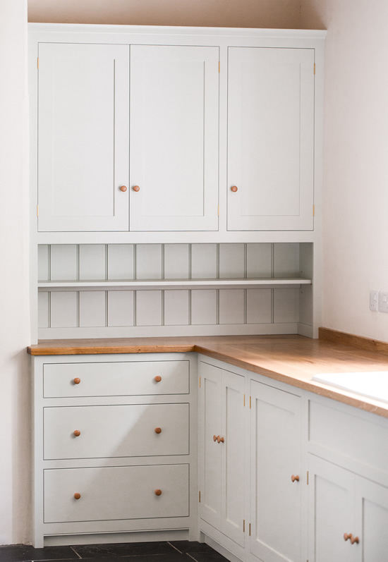 Shaker style kitchen. Birch plywood cabinets with hand painted hardwood frames (Farrow and Ball Estate Eggshell, Pale Powder).Traditional inset sink and integral dishwasher. Inset cooker hob and integral oven. 4.5m full stave oak worktop with upstand. Solid brass hinges and adjustable brass shelf supports. Solid oak dovetailed drawers with painted hardwood fronts. Hand turned beech knobs.