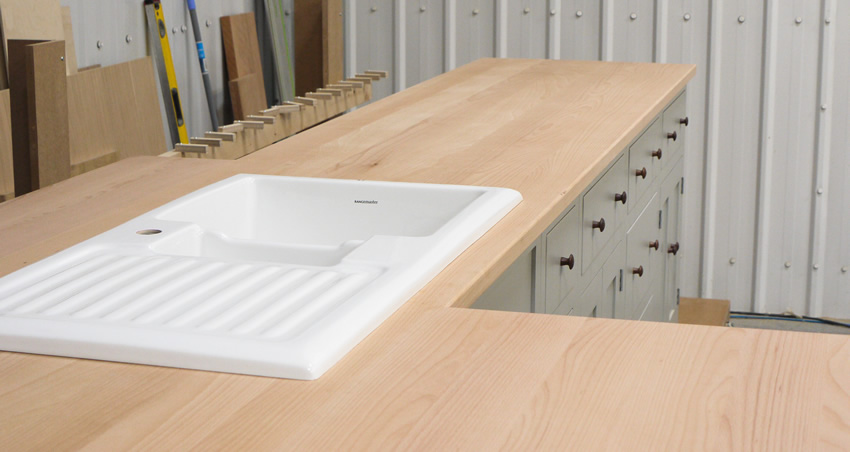 Shaker style kitchen. Birch plywood cabinets with hand painted hardwood frames (Farrow and Ball, Lamp Room Gray). Sink area with integral dishwasher, traditional ceramic inset sink and full stave beech top and upstand. Dovetailed drawers made of solid beech with painted hardwood fronts and walnut hand turned knobs.