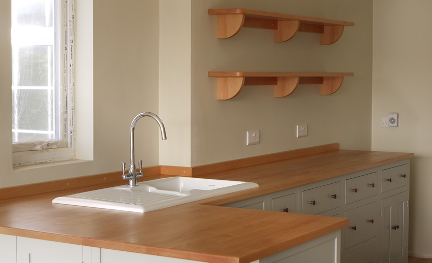 Shaker style kitchen. Birch plywood cabinets with hand painted hardwood frames (Farrow and Ball, Lamp Room Gray). Sink area with integral dishwasher, traditional ceramic inset sink and full stave beech top and upstand. Dovetailed drawers made of solid beech with painted hardwood fronts and walnut hand turned knobs.