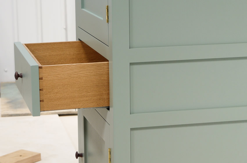 Small larder cupboard handpainted in Farrow and Ball Estate Eggshell - Castle Gray. Solid maple carcass construction with birch ply panels and shelves. Oak dovetailed drawers and oak cornice.
