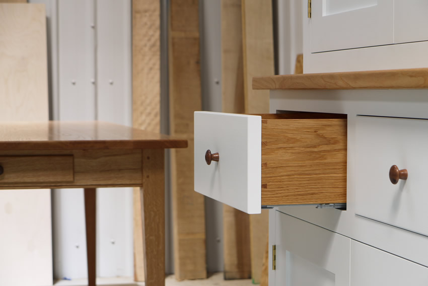 Two part dresser/larder handpainted in Farrow and Ball Estate Eggshell - 'Cabbage White'. Tulip wood carcass with birch ply panels and shelves. Oak dovetailed drawers and oak cornice. Hand-turned walnut knobs and pulls. Oak Shaker style table with tapered legs and oak dovetailed drawer. 