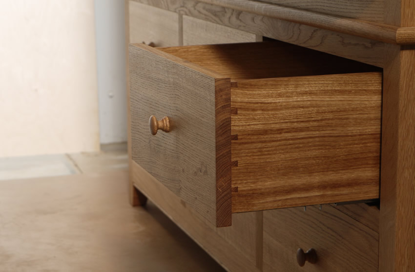 Oak wardrobe with solid oak carcass and panels. Oak faced birch ply shelves. Dovetailed oak drawers on high quality soft close runners. Bespoke cornice in solid oak and hand turned oak knobs. Solid brass hinges and adjustable shelf supports.