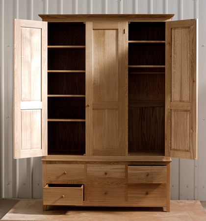 Oak wardrobe with solid oak carcass and panels. Oak faced birch ply shelves. Dovetailed oak drawers on high quality soft close runners. Bespoke cornice in solid oak and hand turned oak knobs. Solid brass hinges and adjustable shelf supports.